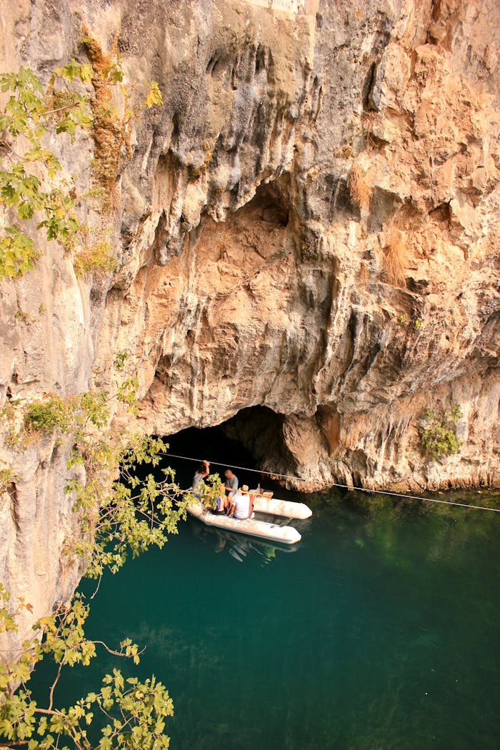 People discovering a scenic cave entrance by inflatable boat.