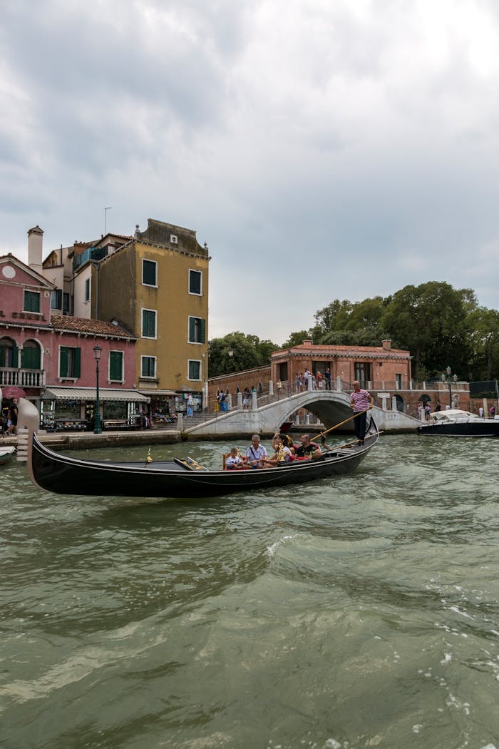 A picturesque gondola ride with tourists on a canal in Venice, showcasing iconic Italian architecture.
